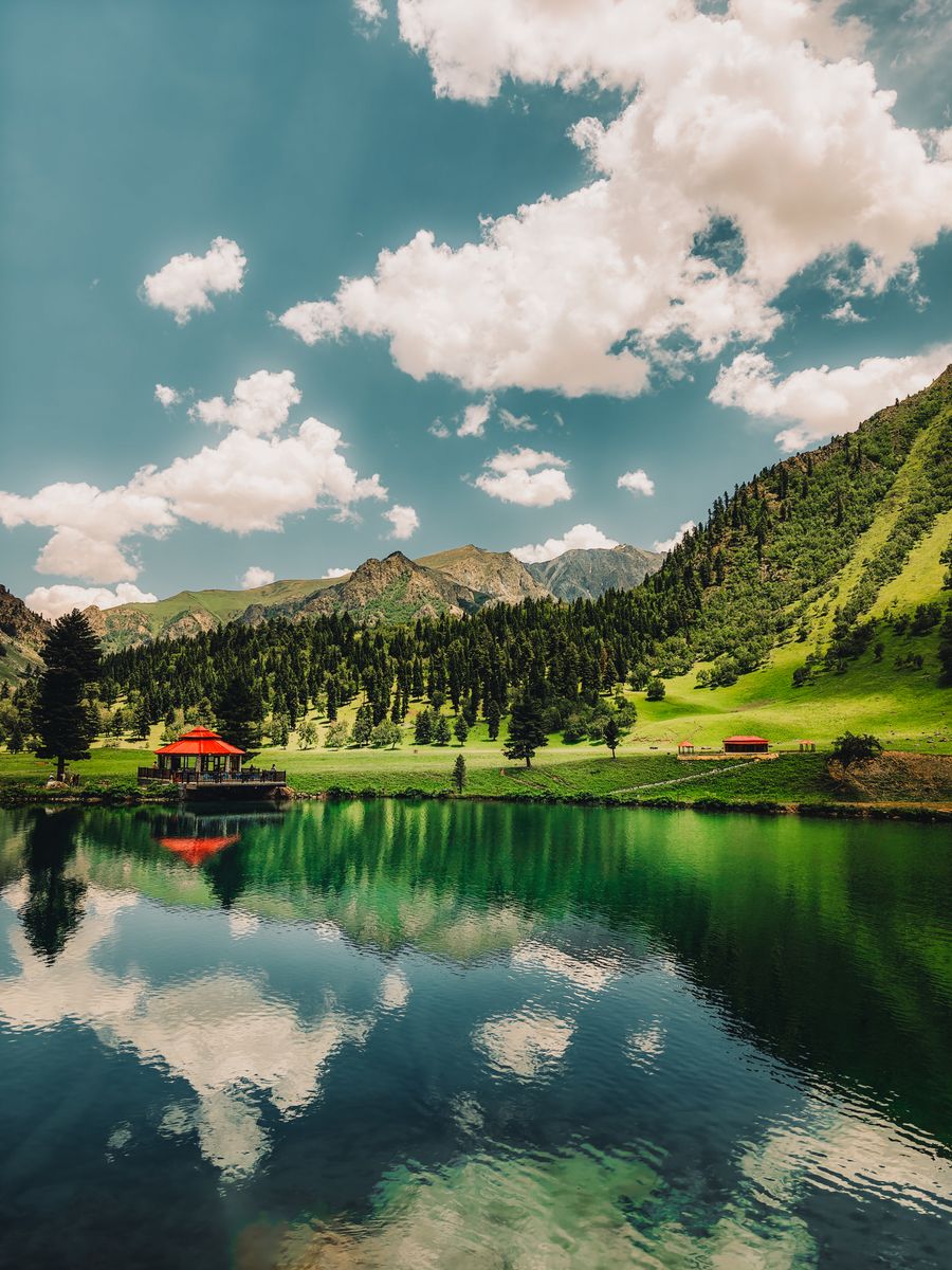 A tranquil mountain lake surrounded by green hills in Skardu, Pakistan